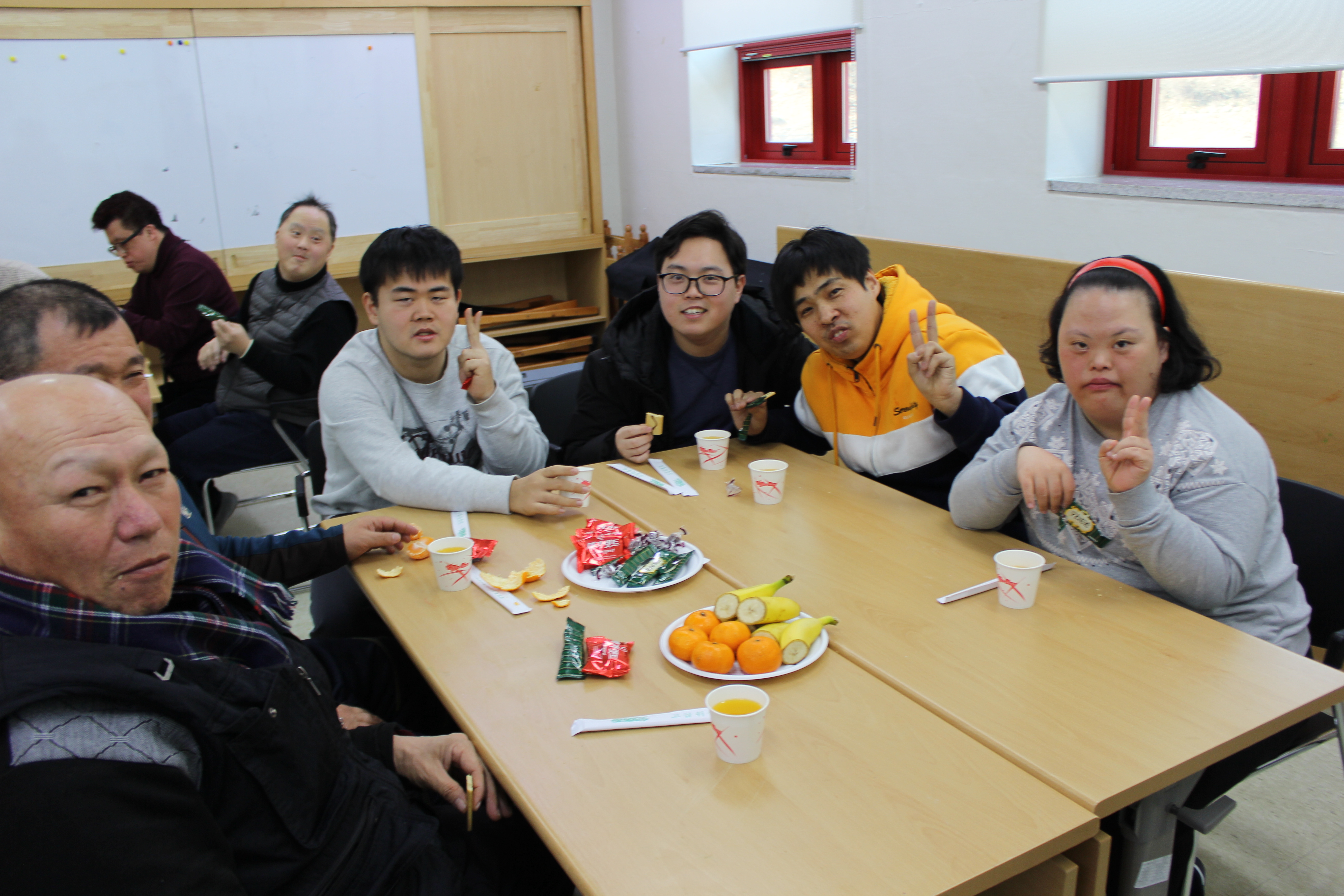 테이블에 다과를 즐기며 기념촬영을 하고 있는 생일잔치에 참여한 이용자들의 모습