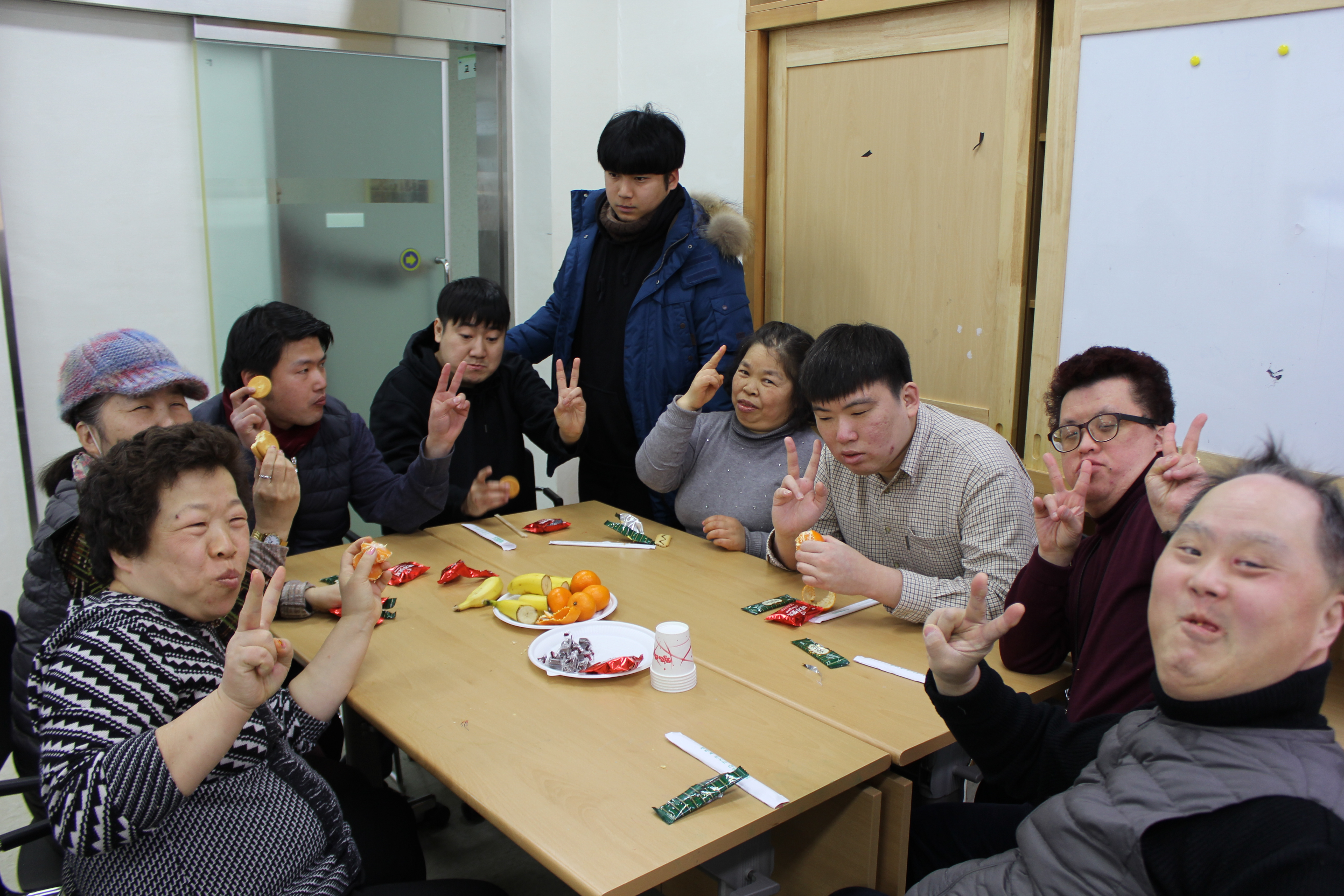 테이블에 다과를 즐기며 기념촬영을 하고 있는 생일잔치에 참여한 이용자들의 모습